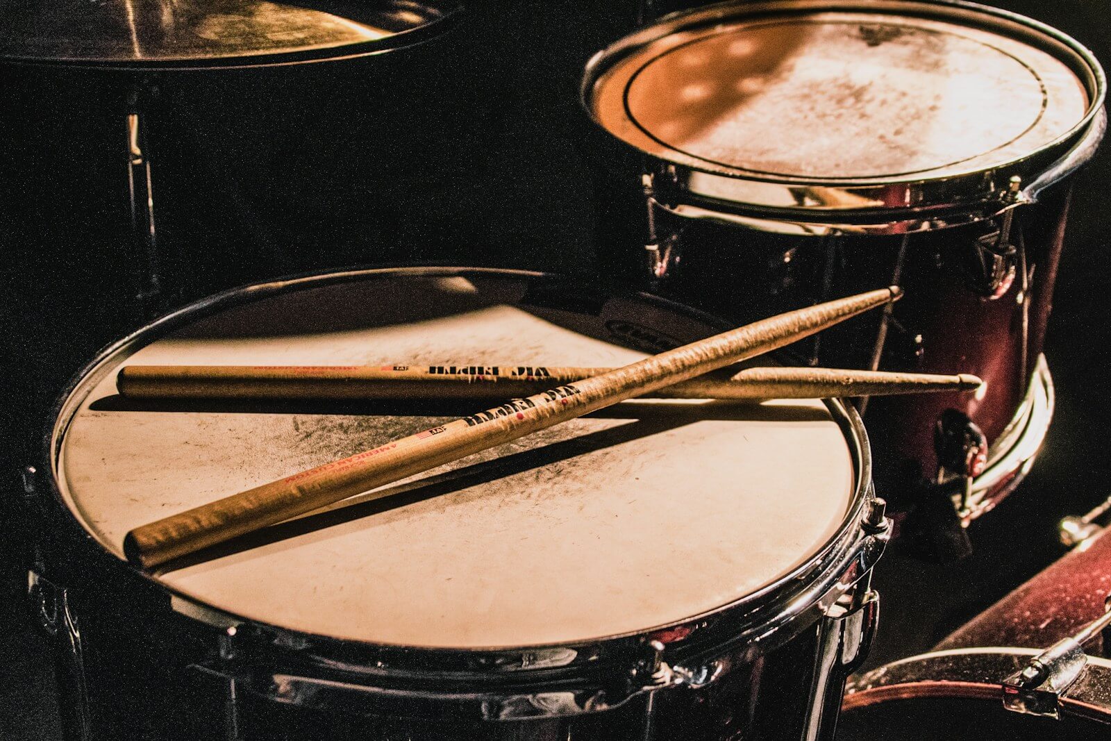 pair of brown wooden drumsticks on top of white and gray musical drum